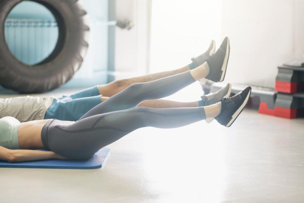 Two people working out on the floor - just their legs showing