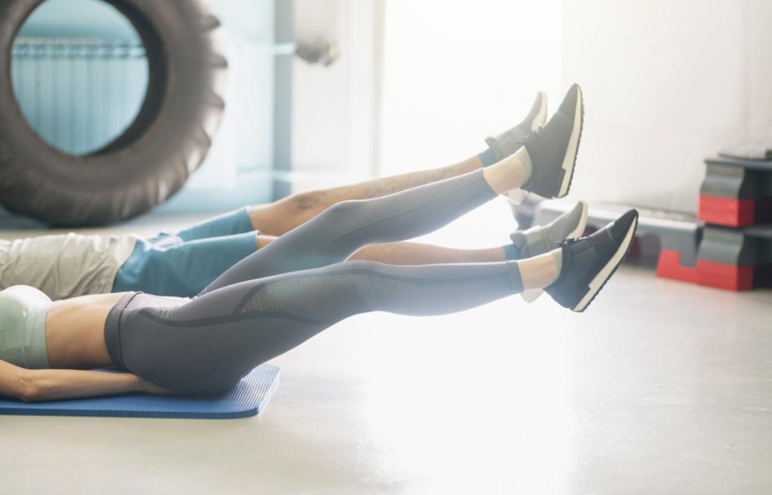 Two people working out on the floor - just their legs showing